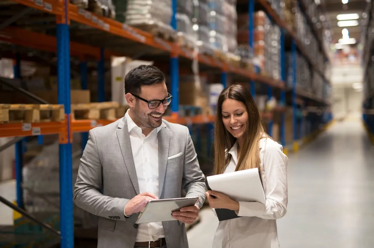 Two colleagues reviewing stock on a tablet in a warehouse aisle