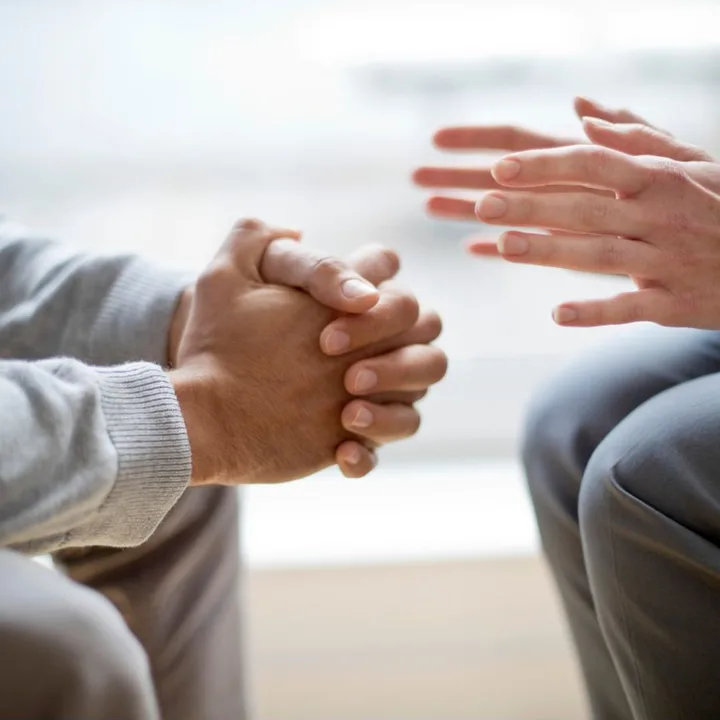 Two men in conversation, one with his hands clasped